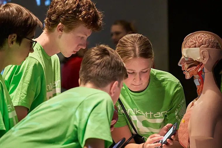 Fyra ungdomar tittar på en mobiltelefon.