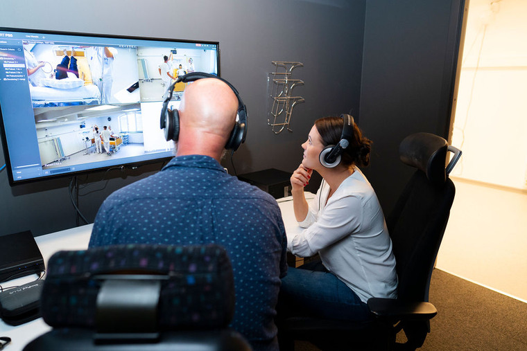 Två lärare tittar på simuleringsövning på en tv-skärm.
