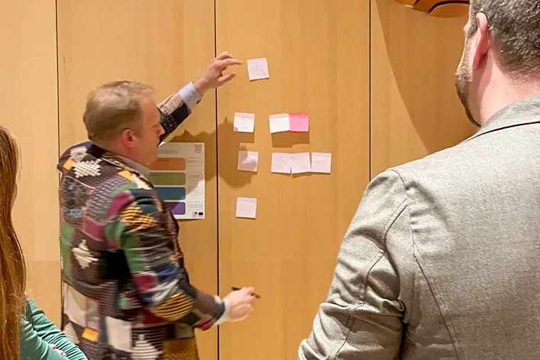Konferensdeltagare s&auml;tter upp Post-it-lappar.
