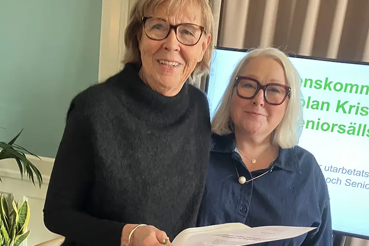 Två personer, den ena håller i ett papper.