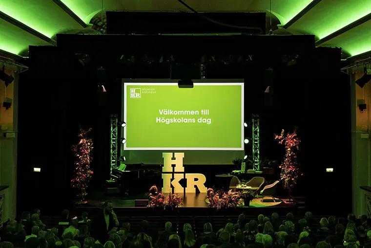 Scen med gr&ouml;n bakgrundsbild med texten V&auml;lkommen till h&ouml;gskolans dag.