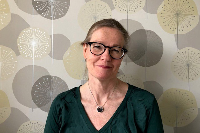 Lektor Malin Sundström framför en mönstrad tapet