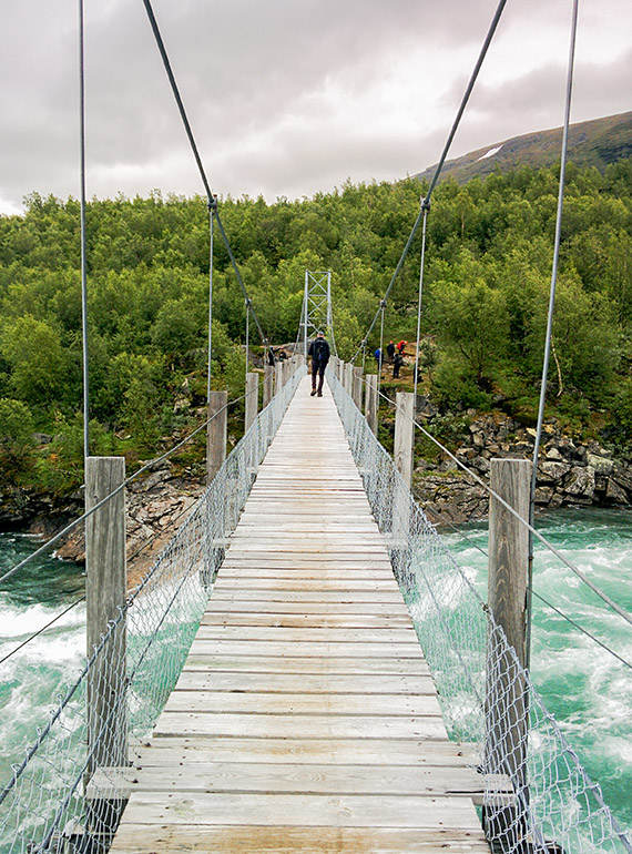 Två personer åt gången får passera över den 61 meter långa hängbron över älven Vuojatädno. Dagsturen går mot Hambergs glaciär. Foto: Johanna Grönroos