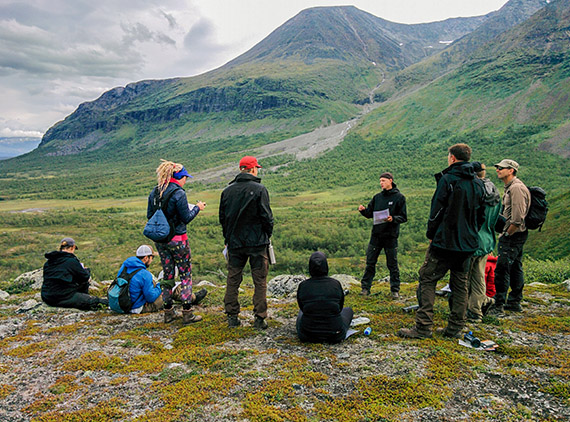 Magnus Redegard föreläser om hur jaktfalken gör när den jagar ripor i området. I bakgrunden reser sig det över tvåtusen meter höga Akkamassivet. Foto: Johanna Grönroos