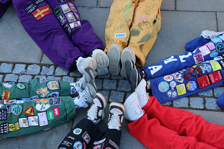 Sex par ben iklädda studentkårsoveraller i olika färger.