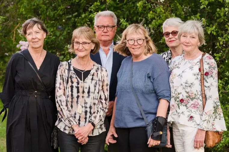 Sex personer st&aring;r utomhus med gr&ouml;na tr&auml;d bakom sig.