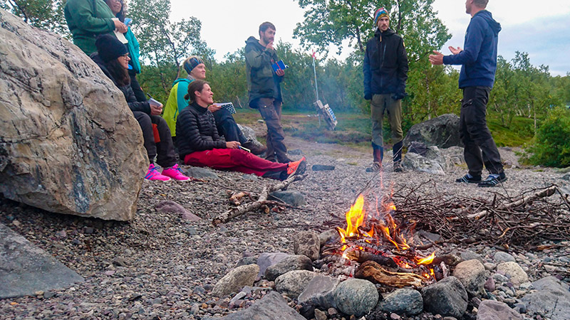 Landskapsvetarstudenten Alexander Lundgren valde att hålla sin presentation nere på Langas strand. Medvetet gav han publiken den fängslande utsikten i fonden medan han förklarade ekosystemtjänsterna i området och elden sprakade. Foto: Fabian Rimfors