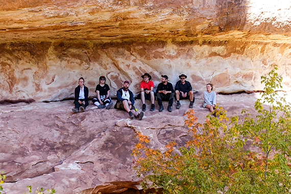 Studenter sitter under en av ”broarna” av sandsten i Natural Bridges National Monument i Utah.