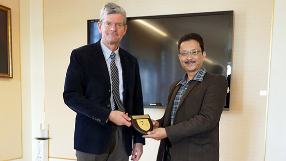 Högskolans rektor Håkan Pihl tar emot gåvan från Swarup Mukherjee, läkare och lärare på avdelningen för lärarutbildning och sport science på Nanyang Technological University i Singapore.