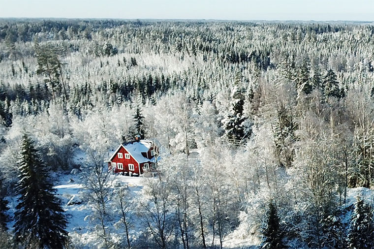 Agnes röda stuga i ett vinterlandskap i skogen.
