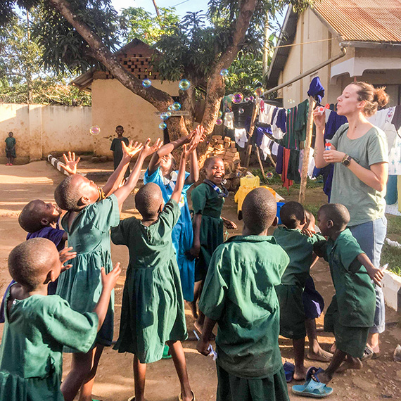 Förskollärarstudenten Anna Hellman blåser såpbubblor tillsammans med barnen på Ssenyange Education Centre.