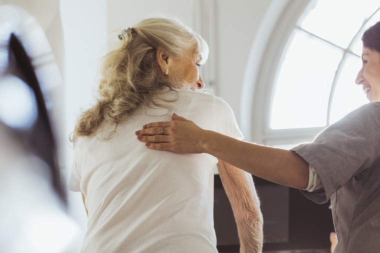 Female caregiver talking with elderly woman exercising on treadmill at retirement home