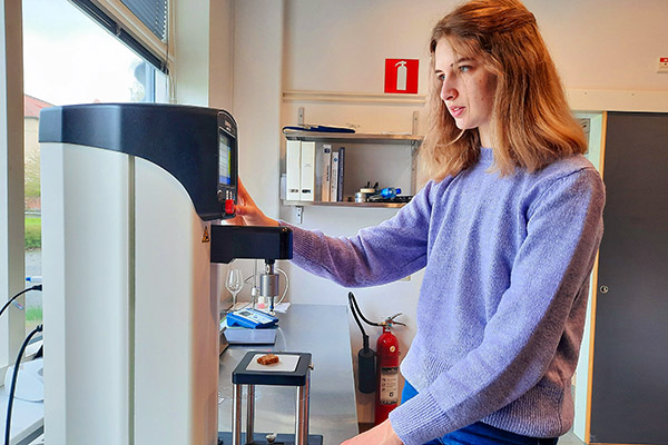 Franska gäststudenten Lucie Borodacz analyserar texturen i en kaka med hjälp av en penetrometer, ett slags hårdhetsmätare.