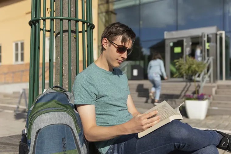 Student l&auml;ser utomhus.