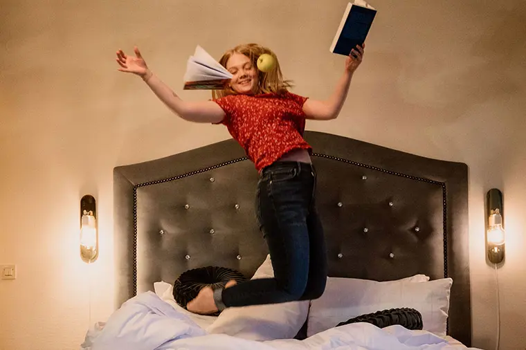 Student pluggar och studsar i säng.