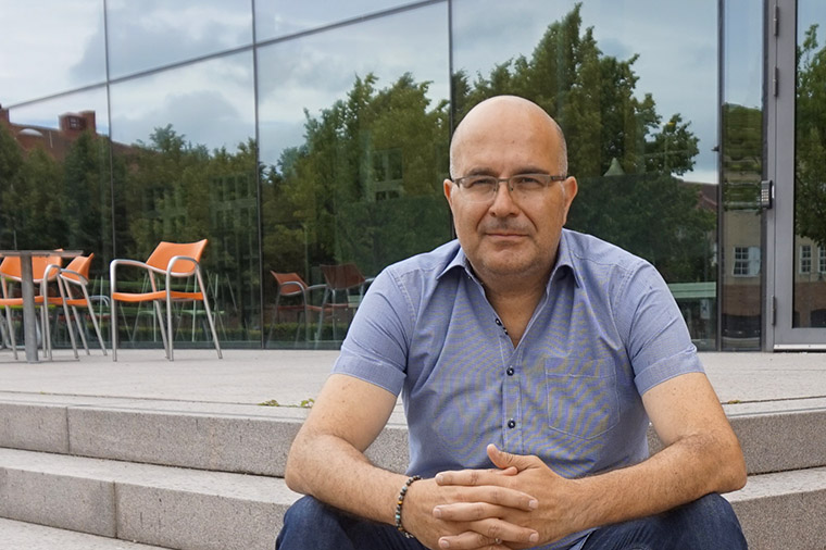 Professor Giuseppe Grossi sitter på trappan till glashuset, Högskolan Kristianstad.