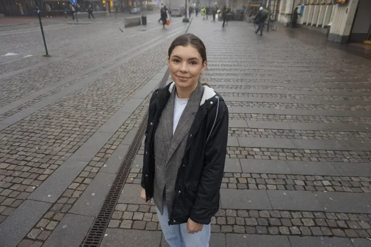 Emelie Farquharson tittar leendes in i kameran, ståendes på en gågata en grå vinterdag.