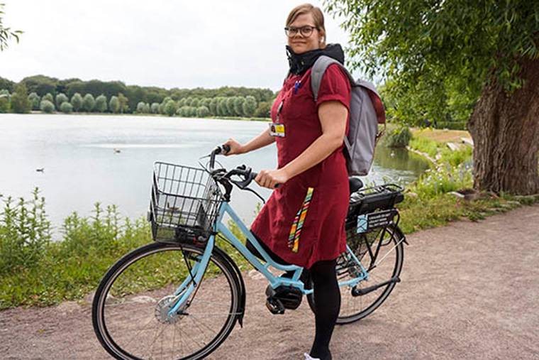 Moa Esse i arbetskläder och på sin cykel.