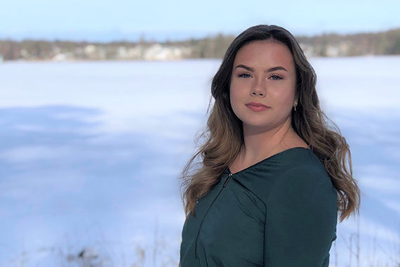 Isabell står i ett vintrigt landskap och tittar in i kameran