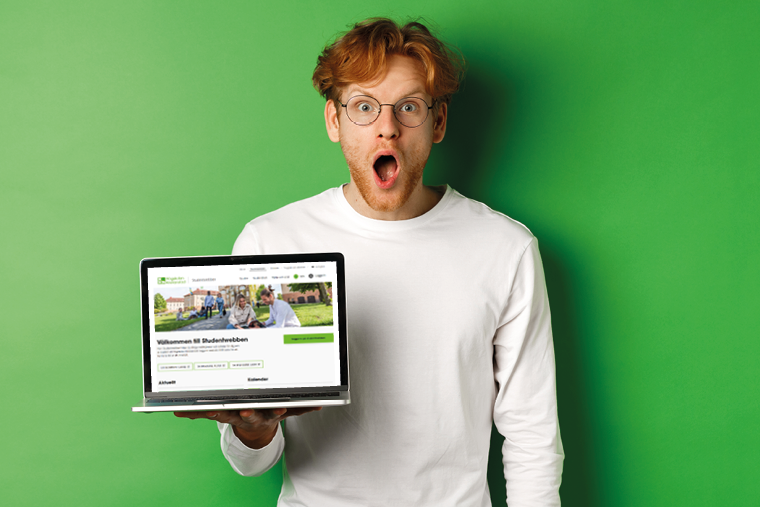 Man h&aring;ller en &ouml;ppnad laptop i handen.
