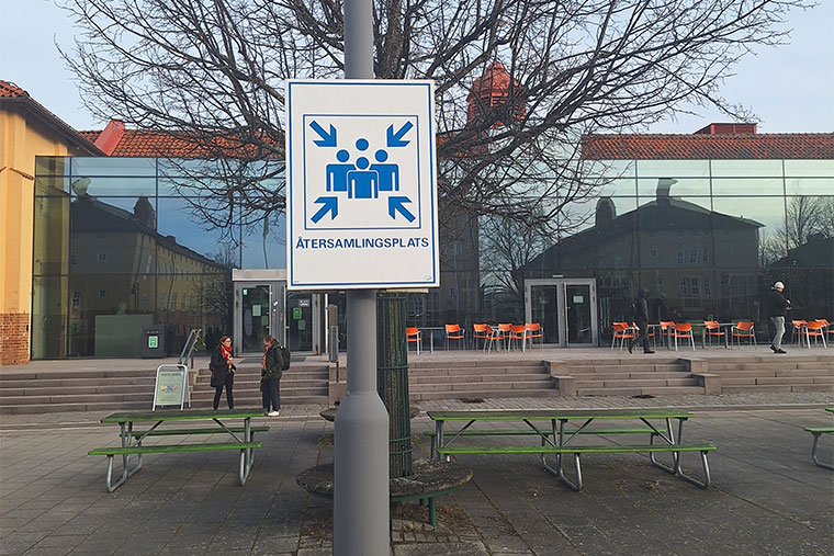 Skylt på återsamlingsplats, grusplanen mellan hus 4 och hus 7