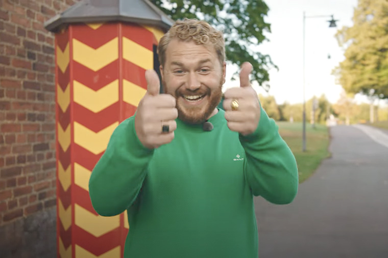 Leende kille iklädd grön tröja  gör tummen upp.