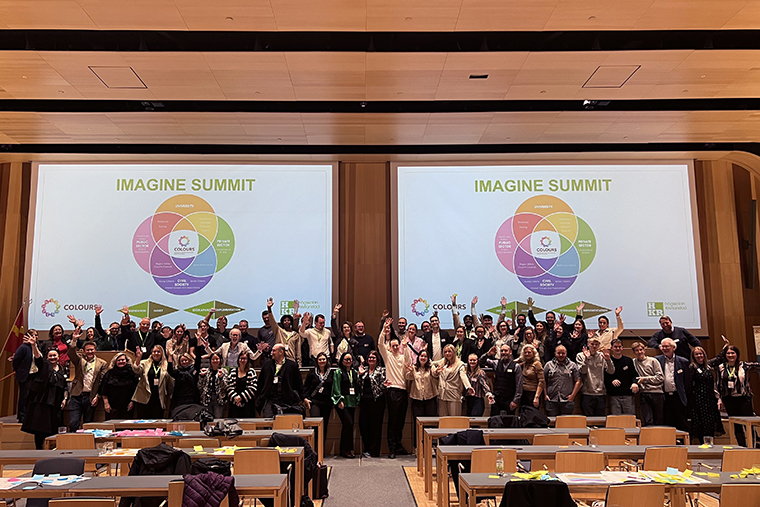 Group of people in front of two screens with the text Imagine Summit.