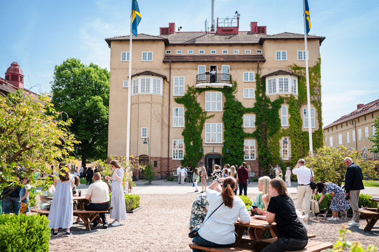 Finklädda människor på ett soligt campus