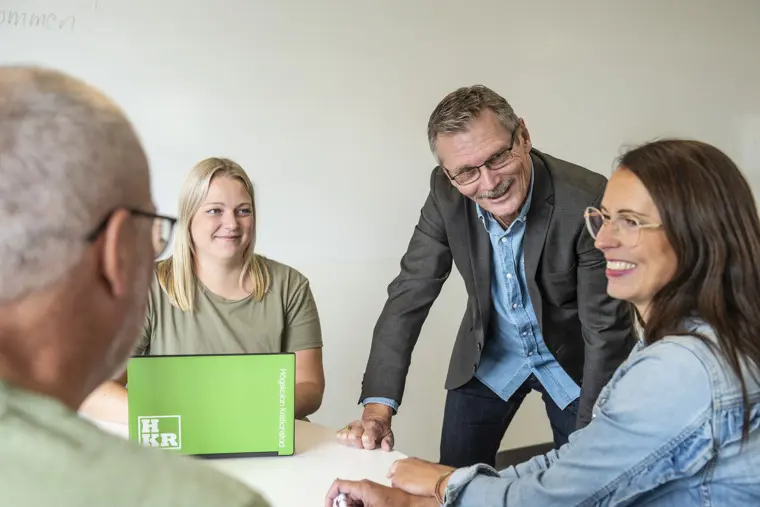 Fyra personer i grupparbete som ler och tittar på varandra.