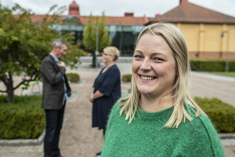 Tre personer utomhus på högskolans campus.