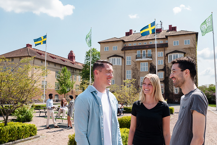 Tre studenter som samtalar på campus en fin sommardag