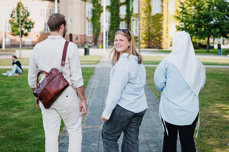 Tre studenter utomhus på högskolans campus.