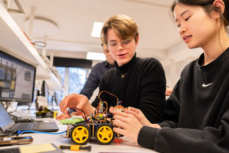 Två studenter arbetar med robot i labbmiljö.