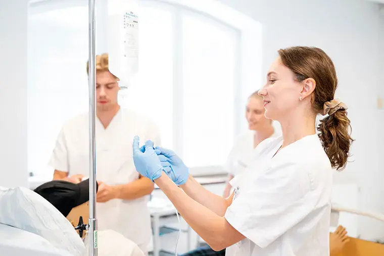 Sjuksköterskestudenter med en droppställning.